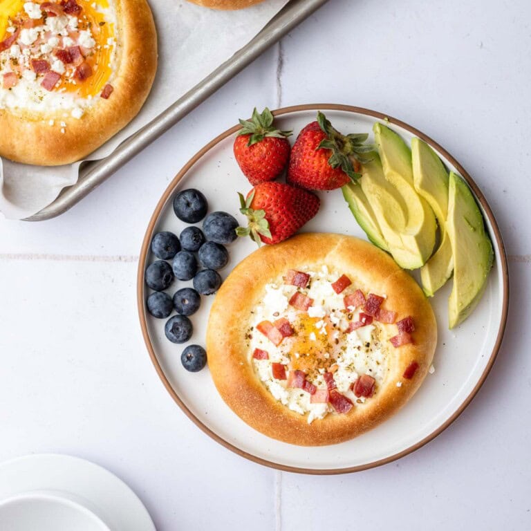 breakfast brioche bun on a plate with fruit and avocado