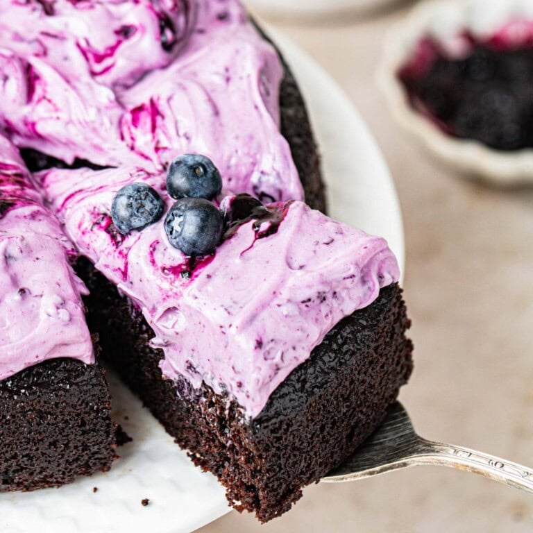blueberry chocolate cake with slice cut out on a cake server