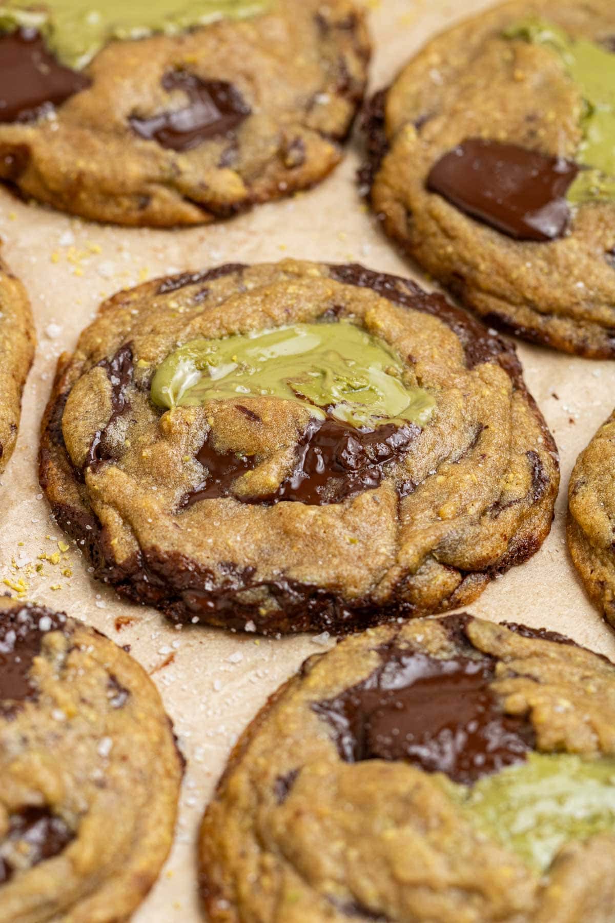 pistachio cream chocolate chip cookies on parchment paper with pools of chocolate