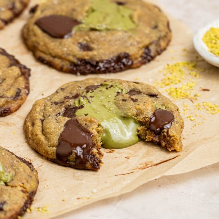 pistachio stuffed cookies on parchment paper with pistachio cream oozing out