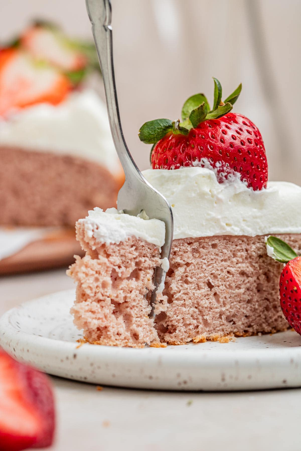 fork cutting into slice of strawberry cake
