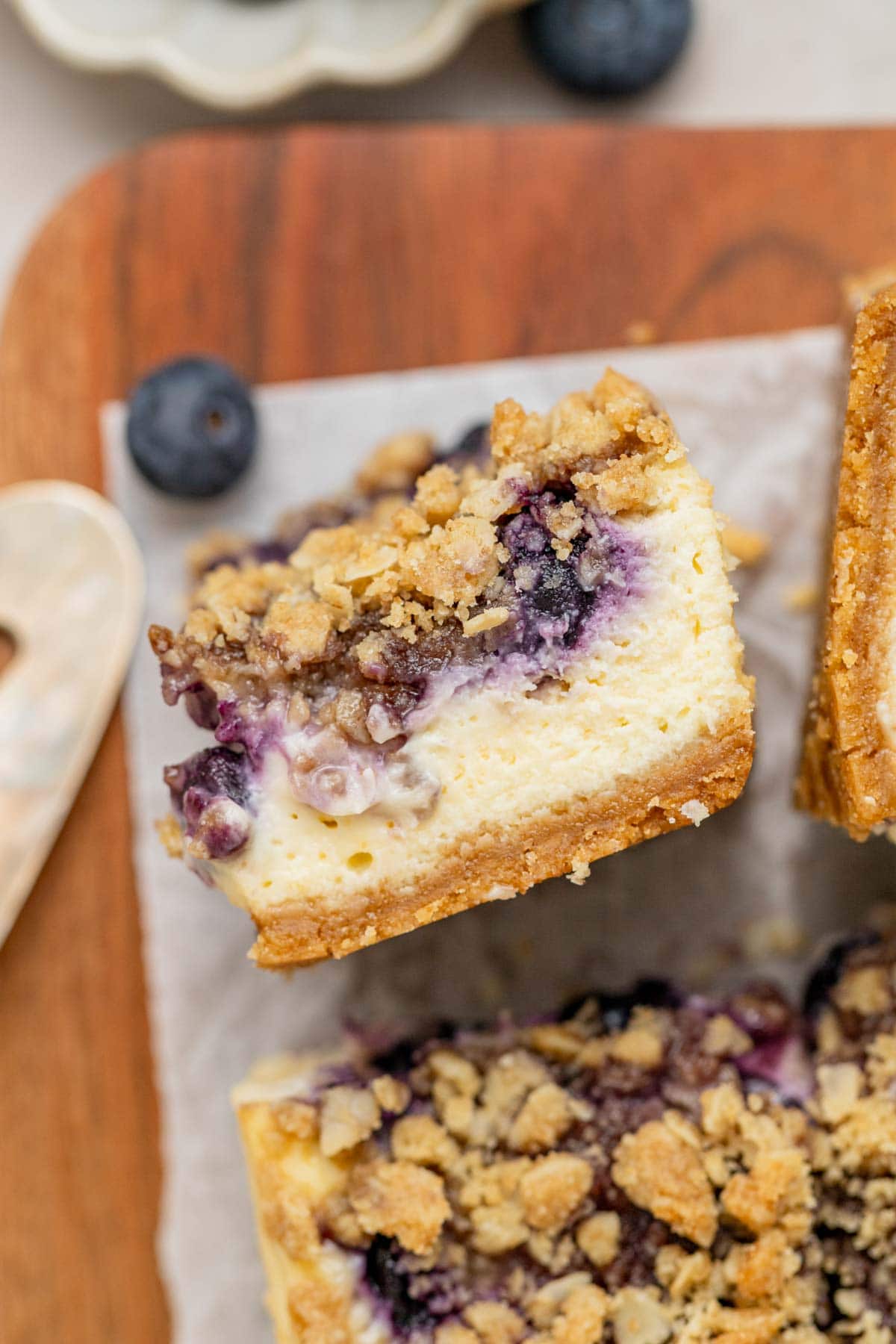 layers of blueberry cheesecake with blueberries and crumble topping