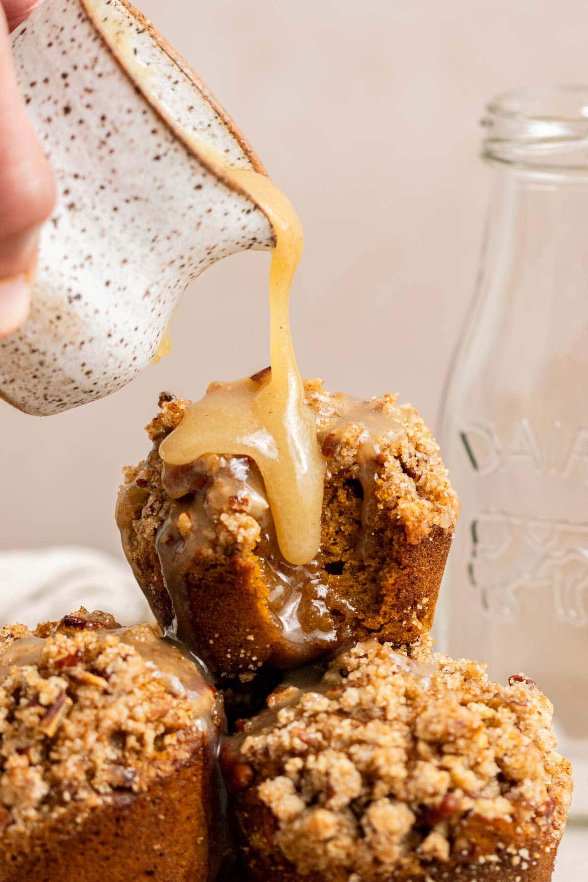 drizzling maple glaze all over pumpkin muffins
