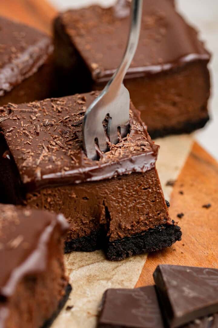 fork cutting into chocolate cheesecake bars