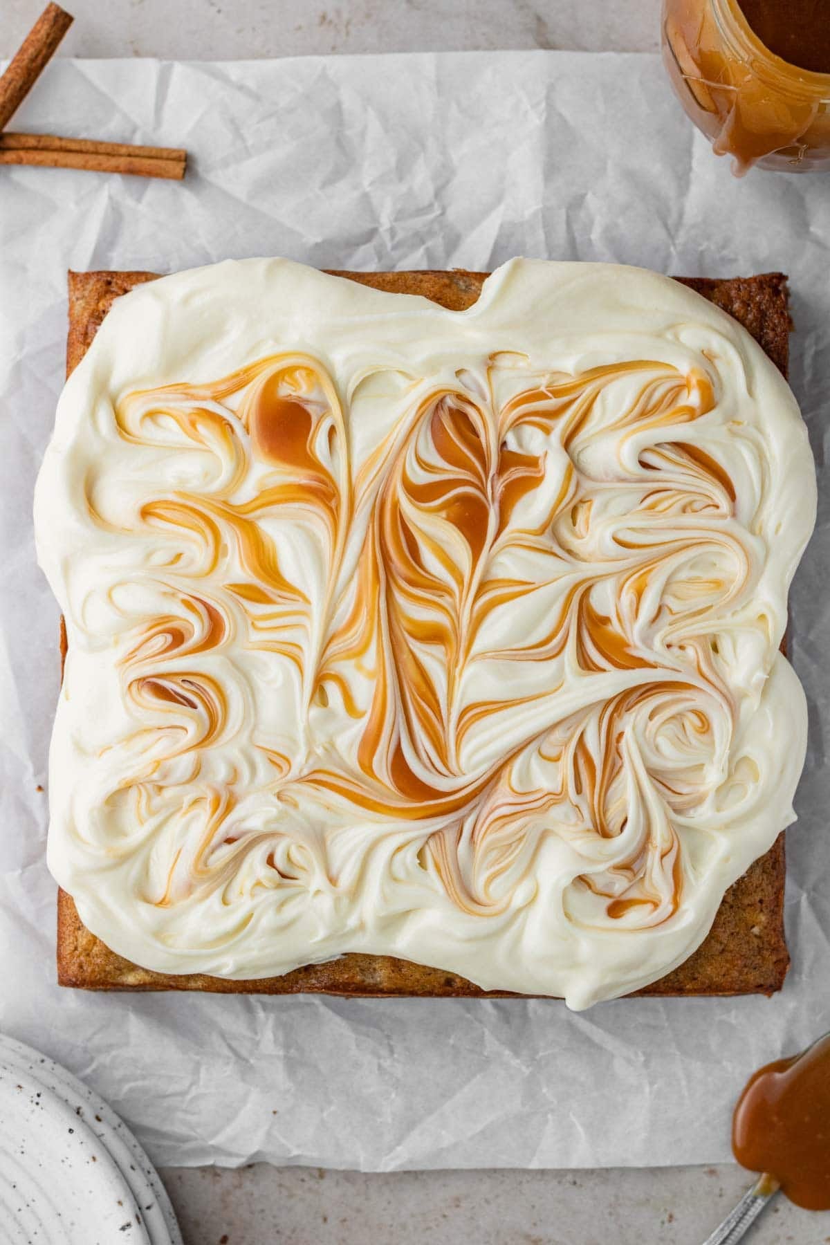 spiced banana cake before slicing topped with cream cheese frosting and caramel sauce