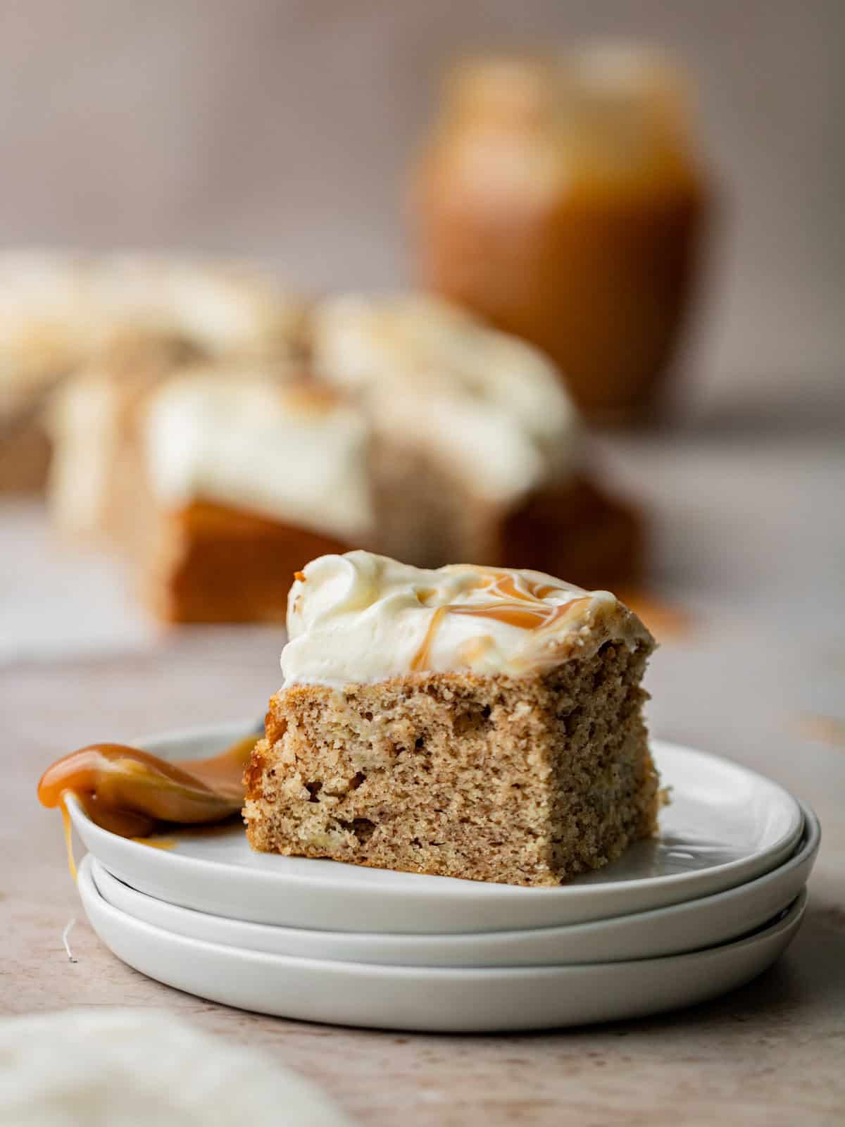 a slice of banana cake on a plate with caramel sauce jar
